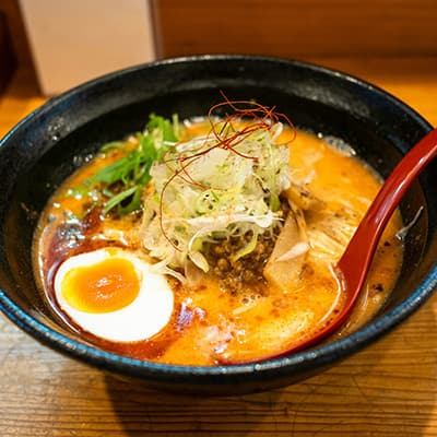 A bowl of ramen with egg, pork and spring onion